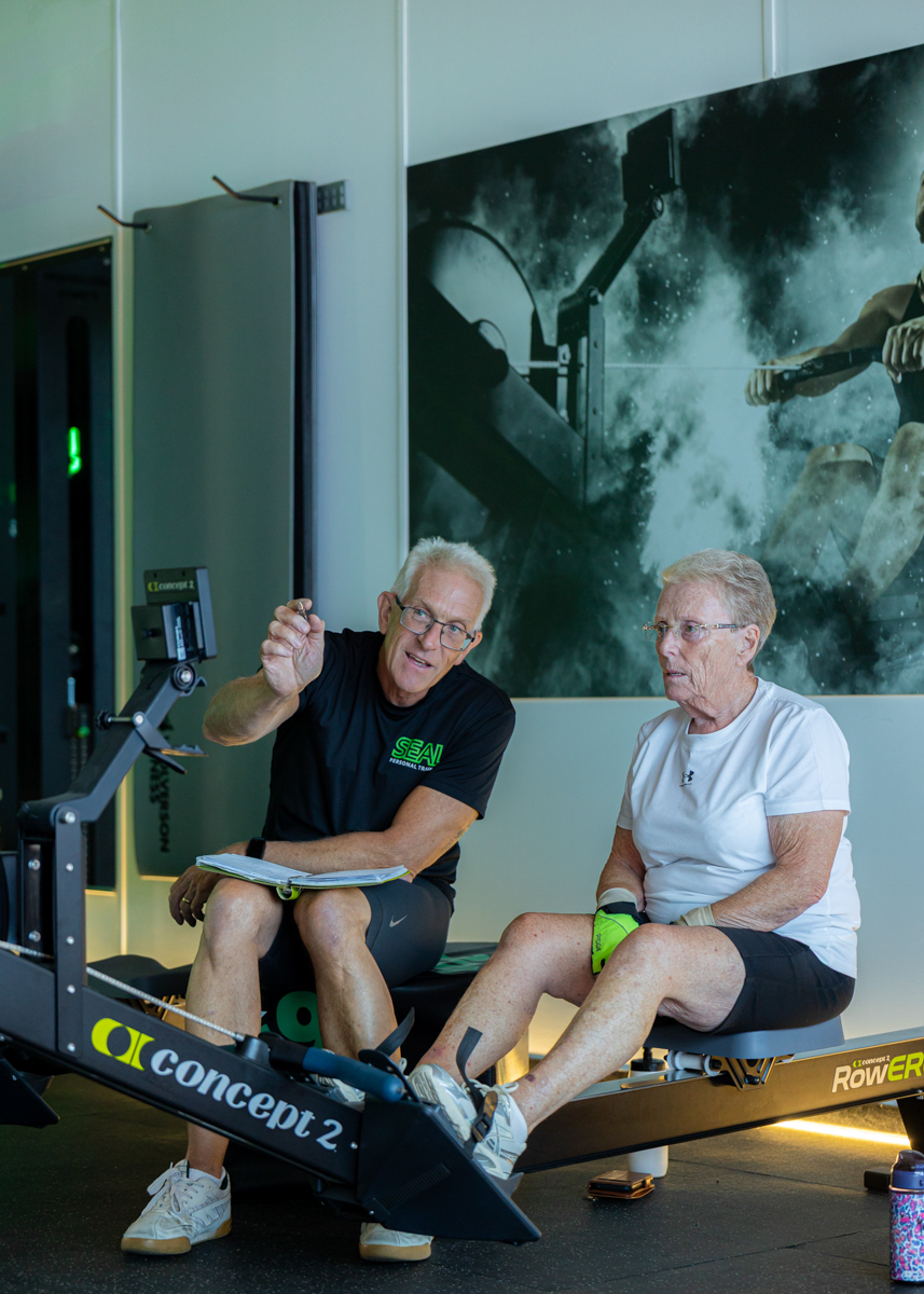 Coach guiding a member through indoor rowing technique